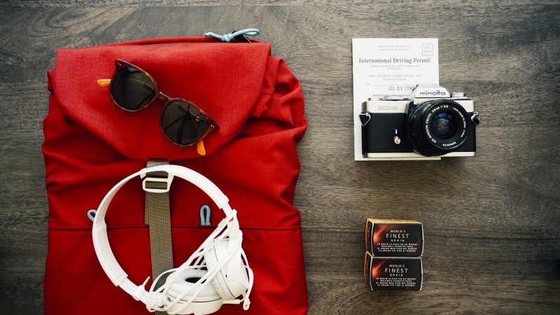 aerial-view-of-red-backpack-with-sunglasses-headphones-and-camera